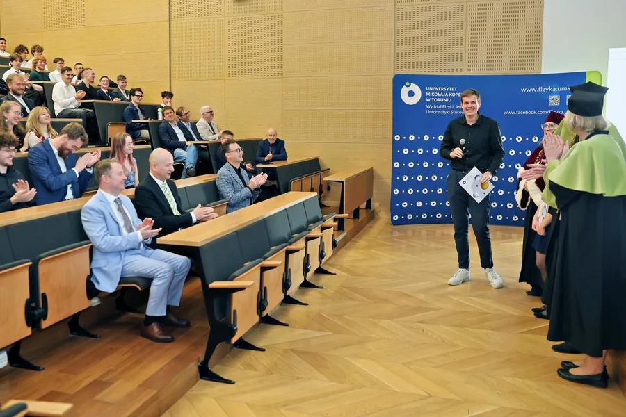 Dariusz Kierski holding his certificate as the audience applauds